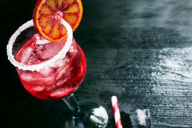 Cocktail in a glass with ice, border and a slice of blood orange, space for text