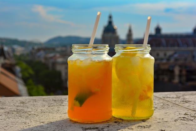 Коктейльные бокалы с освежающим лимонадом на столе в баре на крыше с видом на город