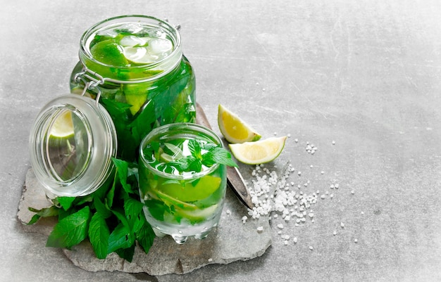Cocktail in jar - mint leaves, ice, rum and lime on a stone base with a knife for citrus and sugar .
