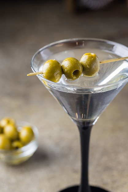 Cocktail martini with olives on gray stone.