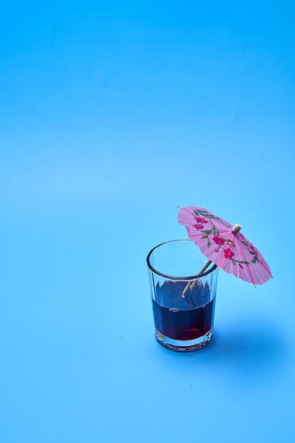 Cocktail met een roze paraplu op een blauwe achtergrond