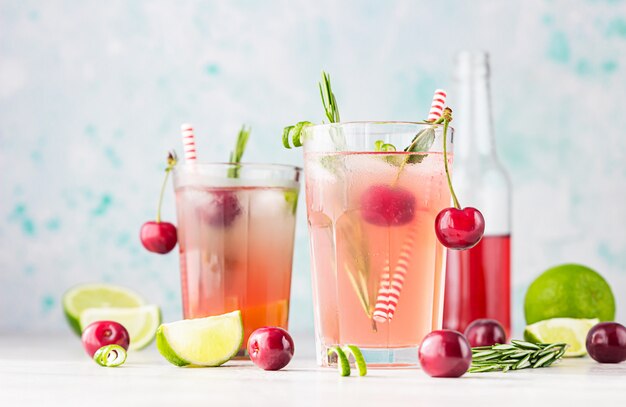 Cocktail of limonade met kersen, limoen en rozemarijn op een grijze tafel. Zomer verfrissing drankje.