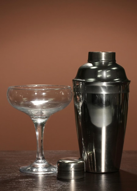 Cocktail shaker and cocktail glass on color background