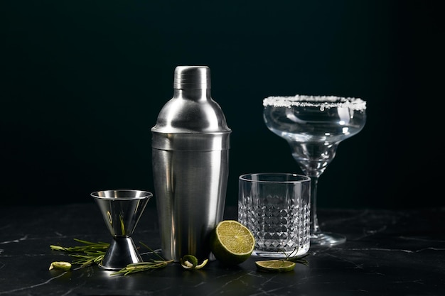 Photo cocktail shaker and cocktail glasses and ingredients on dark marble background