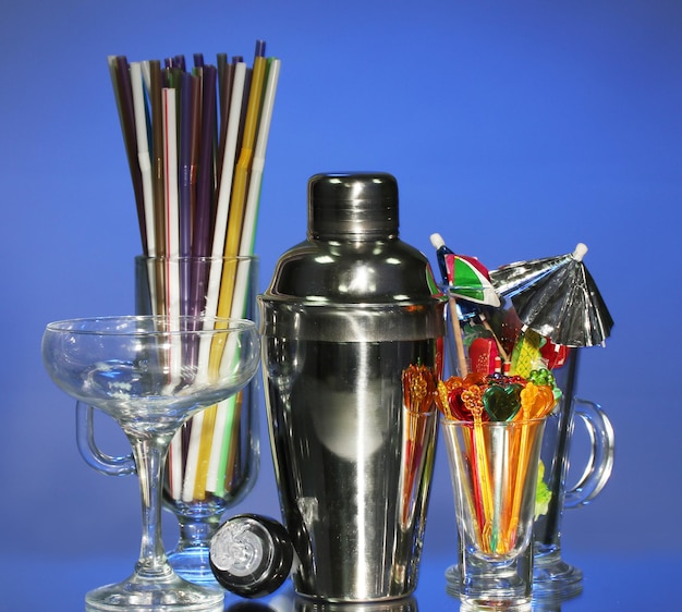 Cocktail shaker and other bartender equipment on color background