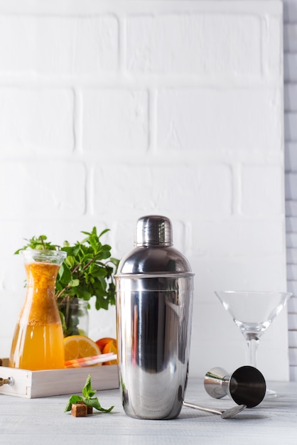 Cocktail shaker, swizzle, tongs and spoon with ice in a bucket for preparing a summer cocktail