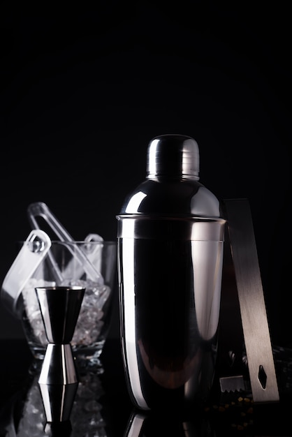 Cocktail shaker, swizzle, tongs and spoon with ice in a bucket for preparing 