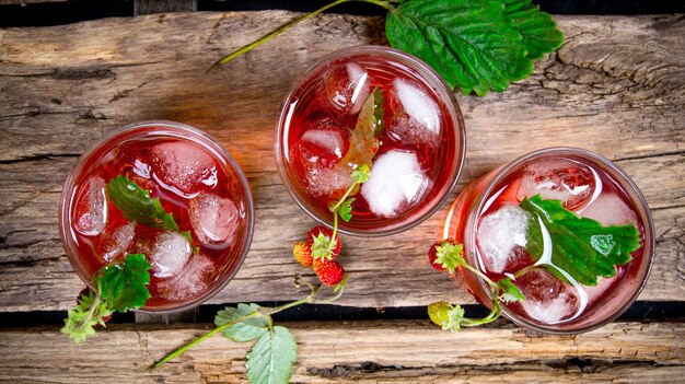 Fragola cocktail. un cocktail di fragoline di bosco con ghiaccio su un tavolo di legno. vista dall'alto