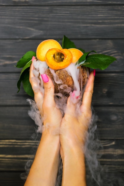 Foto cocktail van fruit en rook in een kokosnoot in vrouwelijke handen 6