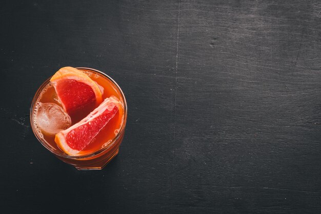 Cocktail of whiskey and grapefruit juice On a wooden black background Top view Copy space