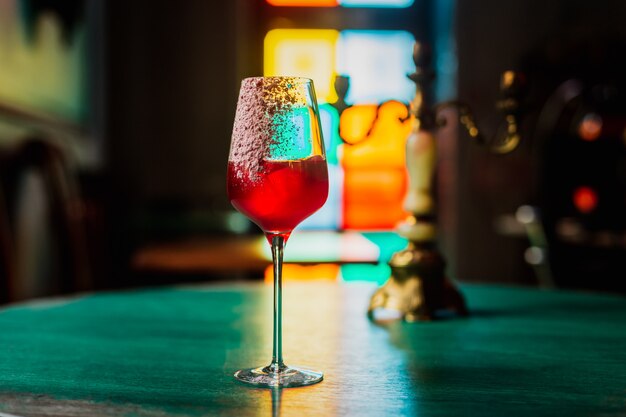 cocktail in a wine glass with an ice cube