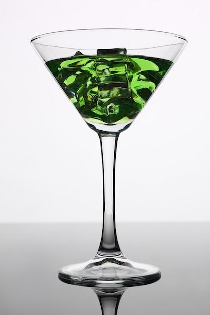 Cocktail with alcohol in green color and ice cubes