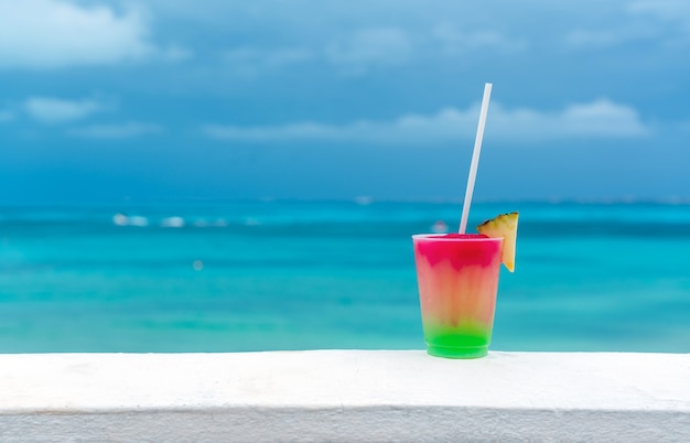 Cocktail with caribbean sea on background concept of beautiful tropical vacation