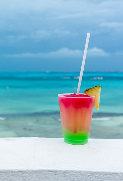 Cocktail with caribbean sea on background concept of beautiful tropical vacation