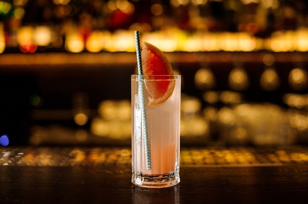 Cocktail with grapefruit decorated with tubule on the wooden steel bar counter