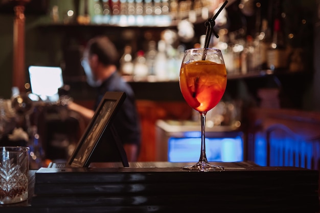 Cocktail with ice and a slice of orange in a glass on the bar