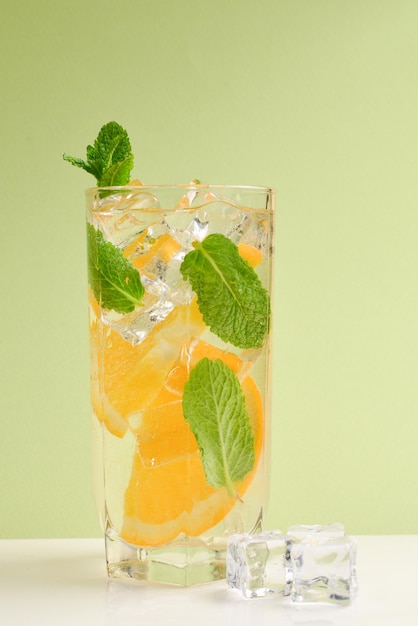 Cocktail with lemon and mint on a green background Copy space