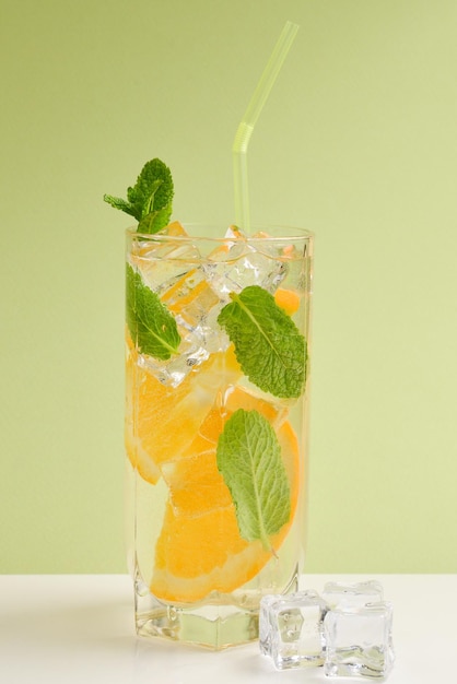 Cocktail with lemon and mint on a green background Copy space