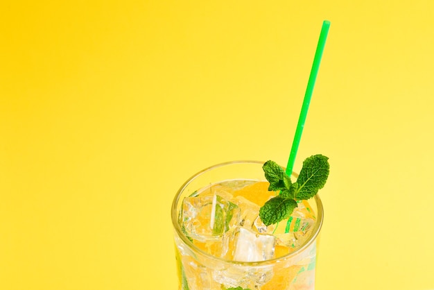 Cocktail with lemon and mint on a yellow