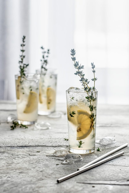 Cocktail with lemon thyme and ice in glasses on table Refreshment detox cocktail or infused water