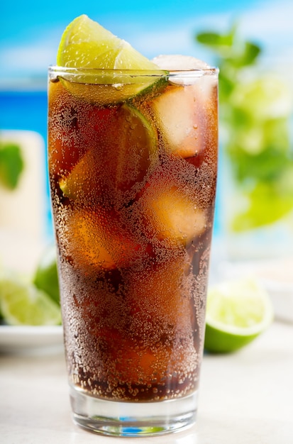 Photo cocktail with lime and cola on beach