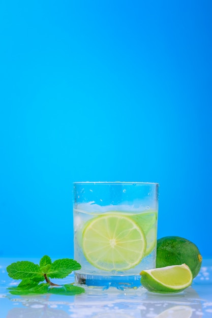 Foto cocktail con lime e menta fresca in vetro su sfondo blu