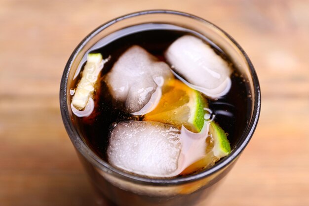 Cocktail with lime slices and ice blocks on wooden table top view