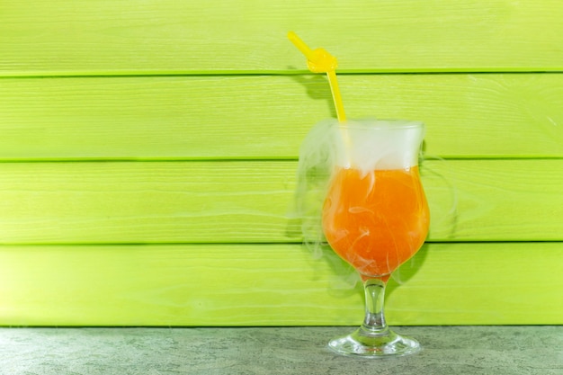 Cocktail with liquid nitrogen. Summer cooling orange cocktail in a glass beaker with a straw. from liquid nitrogen