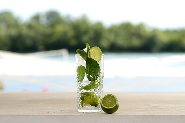 Cocktail with mint and ice in a glass tumbler. With flower and fruit decor