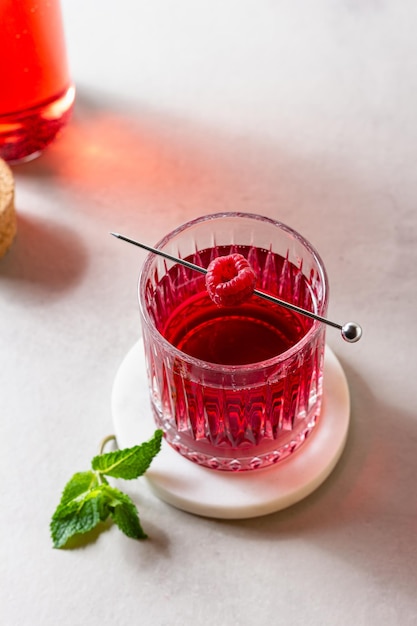 Photo cocktail with raspberry in a glass on a marble stand