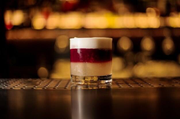 Cocktailglas van kleurrijke schilferige zoete en smakelijke cocktail op de bar