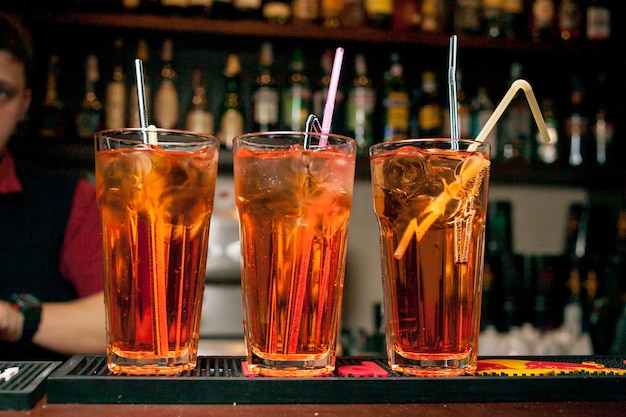 Cocktails in glass jars stand in a row on the table The bartender making alcoholic cocktail