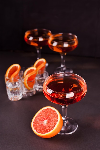 Foto cocktails met sinaasappelsap en sinaasappelschijfjes voor een feestje op een donkere verticale foto als achtergrond