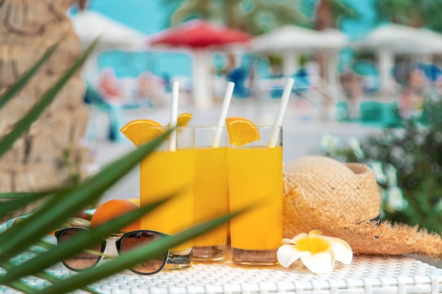 Cocktails, zonnebrillen, strohoed en vers fruit in een witte kom bij het zwembad
