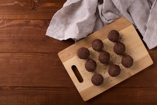 Cocoa balls, chocolate truffles cakes on board on wooden table