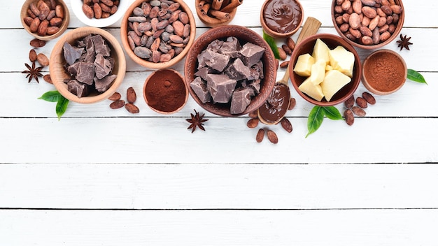 Cocoa beans chocolate cocoa butter and cocoa powder on a white wooden background Top view Free copy space