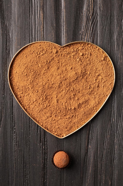 Cocoa in a box in the shape of a heart and sweets on a dark background top view copy space for text