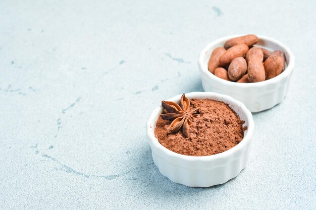 Photo cocoa and cocoa beans in a white bowl on a gray stone background side view