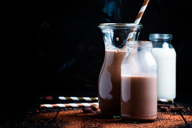 Cocoa or milk with chocolate glass bottles changing background selective focus