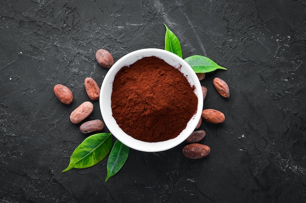 Cocoa powder in a bowl and cocoa bean On a black background Top view Free copy space