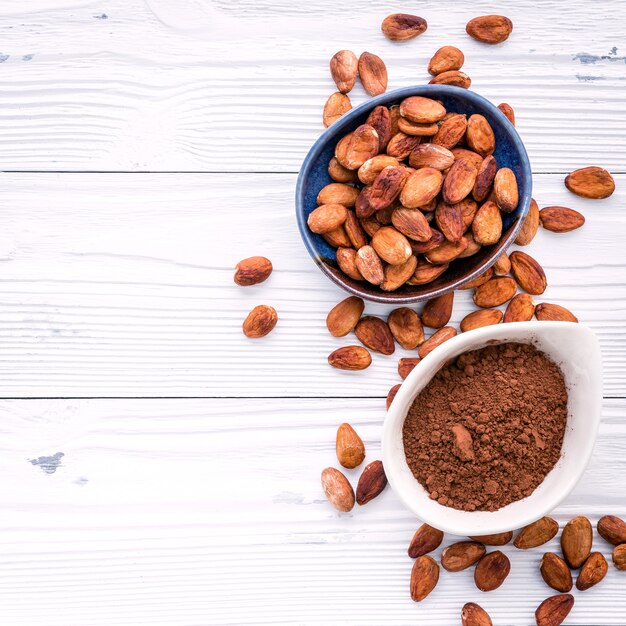 Cocoa powder and cacao beans on wooden background.