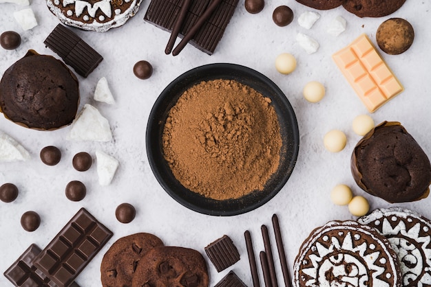 Cocoa powder with chocolate items on white backdrop