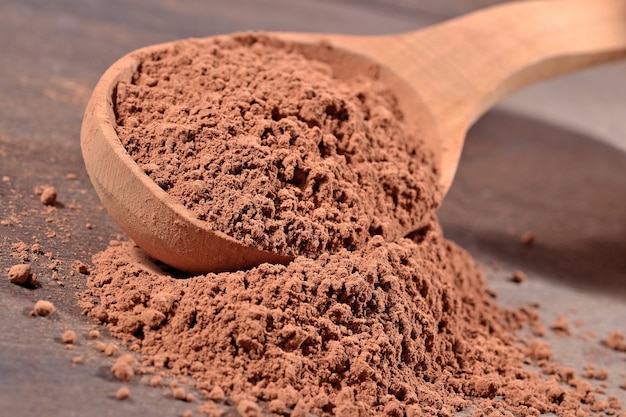 Cacao in polvere in un cucchiaio di legno