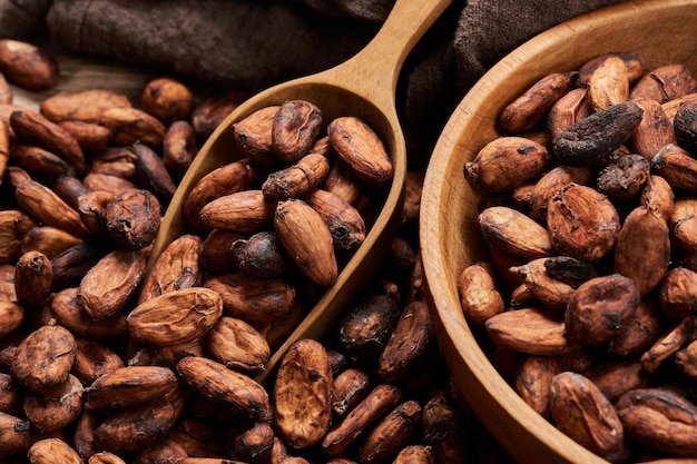 Cocoa seed or cacao beans with wood scoop and bowl in wooden\
table background