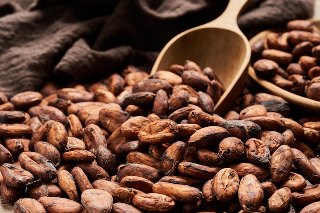 cocoa seed or cacao beans with wood scoop in wooden table background