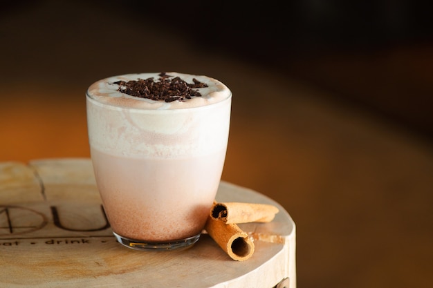 Cocoa with cinnamon and chocolate closeup on wooden stands and dark background.