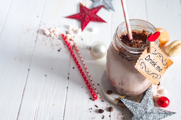 Cocoa with marshmallow and straws in the glass jar decorated with christmas stars 