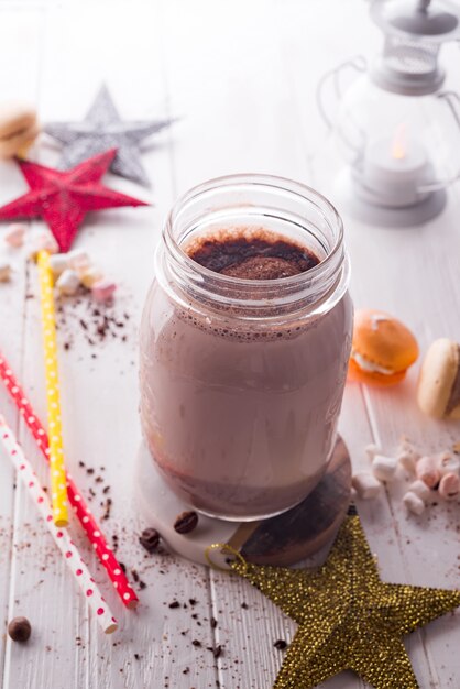 Cocoa with marshmallow and straws in the glass jar decorated with christmas stars