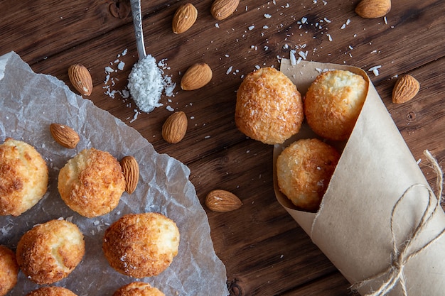 Coconut biscuits with almonds on a board and in a paper bag.