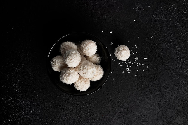 Caramelle al cocco con noci su sfondo scuro raffaello su sfondo nero foto di alta qualità